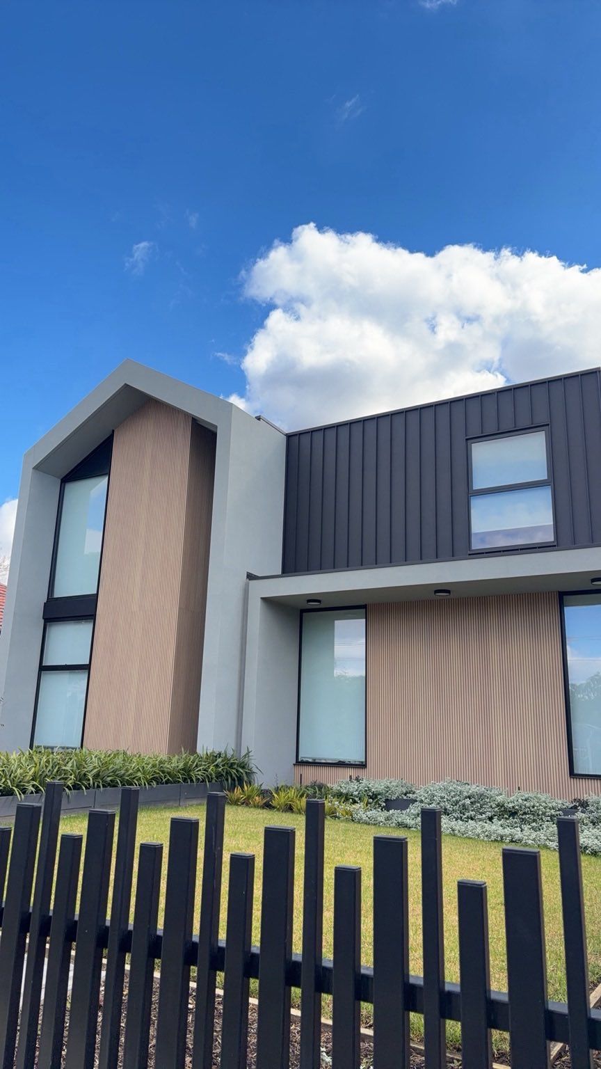 Reference photograph of a modern Melbourne house with angular architecture and a dark vertical fence